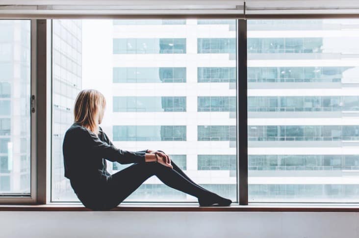 Woman sat on a window ledge pondering